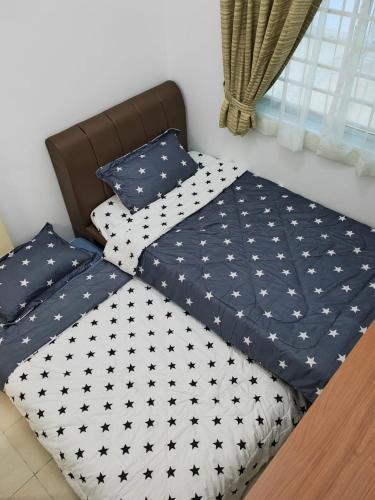 two beds with black and white comforter and pillows at Ann_HomeStay in Sandakan