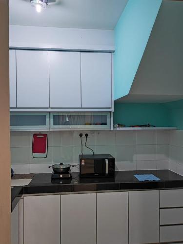 a kitchen with white cabinets and a black counter top at Ann_HomeStay in Sandakan