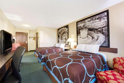 a hotel room with two beds and a flat screen tv at Super 8 by Wyndham Hutchinson in Hutchinson