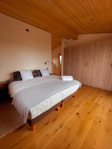 a bedroom with a large bed with a wooden ceiling at Refugio Pullao in Quilquico