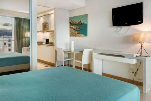 a hotel room with a bed and a desk with a television at Dfm Happy Days D - Funchal in Funchal