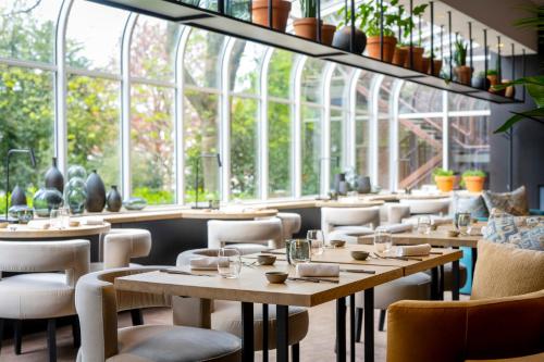um restaurante com mesas, cadeiras e janelas em The Hotel Brussels em Bruxelas