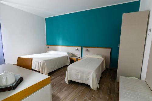 um quarto com duas camas e uma parede azul em Spira Mirabilis Napoli em Nápoles