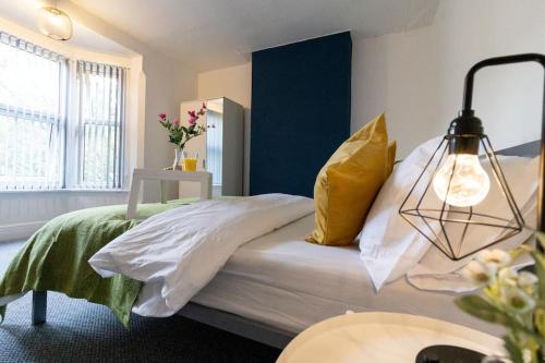 a bedroom with a bed with white sheets and yellow pillows at Room for All Your 4-Bedroom Comfort Zone in Leicester