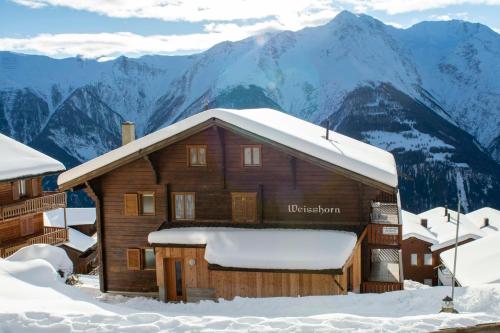 a log cabin in the snow with mountains in the background at Chalet Weisshorn 4 in Bettmeralp