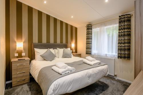 a bedroom with a large bed with towels on it at Woolverstone Marina and Lodge Park in Ipswich