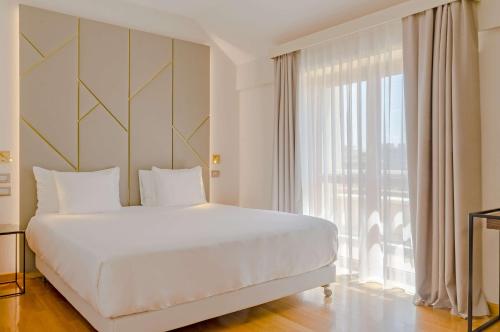 um quarto com uma cama grande e uma janela grande em NH Collection Roma Giustiniano em Roma