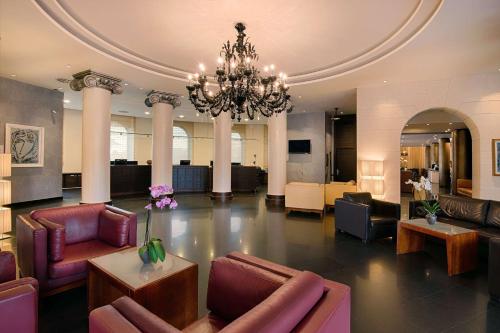 a large lobby with couches and a chandelier at NH Siena in Siena