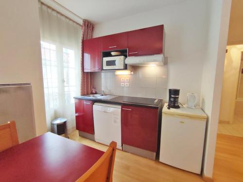une cuisine avec des placards rouges et blancs et une table dans l'établissement Ostal, T3, centre Luchon, wifi, casier à skis, ascenseur, 6 personnes, à Luchon