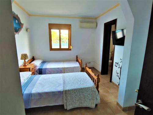 a room with two beds and a television and a window at Es Marroig Villa y Spa in Llucmajor