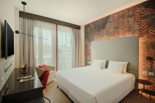 a hotel room with a white bed and a window at NH Collection Milano President in Milan