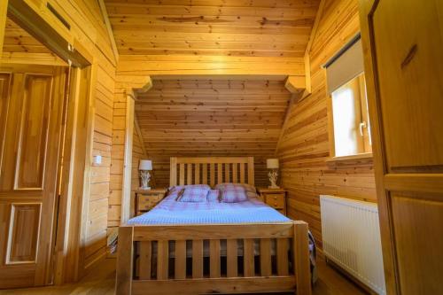 a bedroom with a bed in a wooden cabin at Norwegian Log Cabin The Roe Deer -sauna & hot tub in Keith