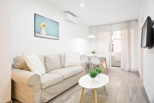 a white living room with a white couch and a table at The White Flats Les Corts in Barcelona