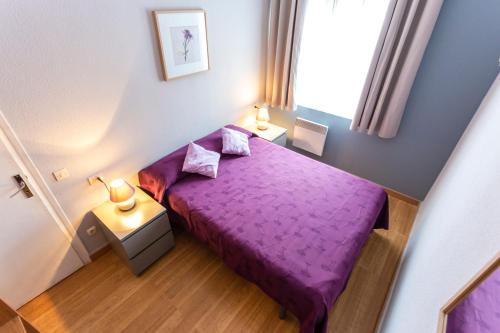 a small bedroom with a purple bed and a window at Gran Duc Pedrous in Pas de la Casa
