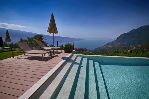 a swimming pool with two chairs and an umbrella at BnB Borgo le Vigne - L'Uva rara Only Adults in Tignale