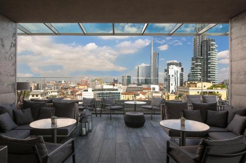 a restaurant with tables and chairs and a view of a city at ME Milan Il Duca in Milan