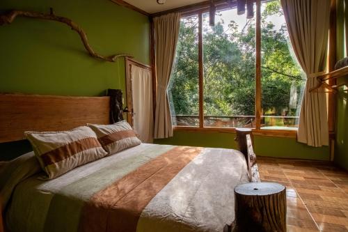 a bedroom with a bed with green walls and a window at Canopy Wonders Vacation Home in Monteverde Costa Rica