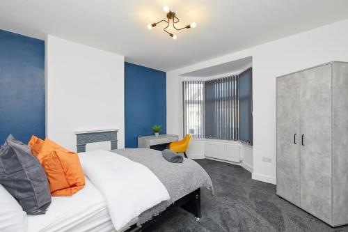 a bedroom with a bed and a blue wall at Sleek & Stylish Modern 4-Bedroom Urban Retreat in Leicester