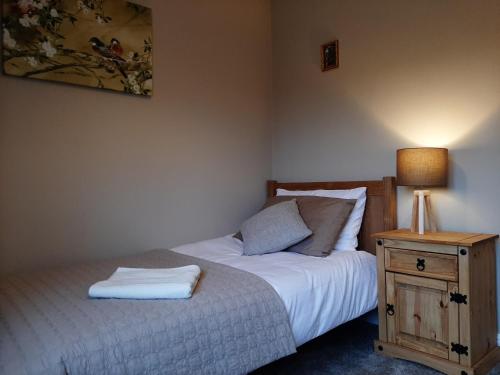 a bedroom with a bed and a table with a lamp at Maria`s Garden House in Ollerton
