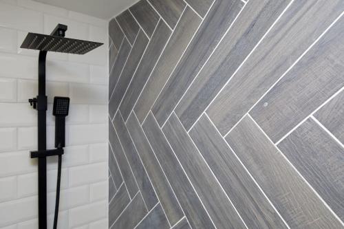 La salle de bains est pourvue d'une douche avec un mur en métal. dans l'établissement Sleek & Stylish Modern 4-Bedroom Urban Retreat, à Leicester