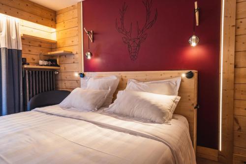 a bed with white pillows and a red wall at Chalet-Hôtel La Marmotte, La Tapiaz & SPA, The Originals Relais in Les Gets
