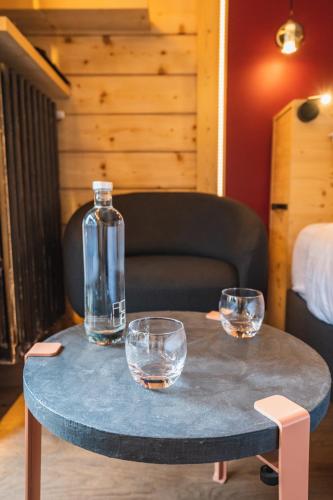 a table with three glasses and a bottle on it at Chalet-Hôtel La Marmotte, La Tapiaz & SPA, The Originals Relais in Les Gets