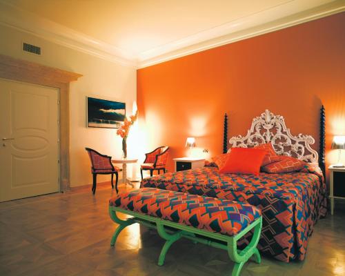 a bedroom with a bed with an orange wall at Byblos Art Hotel Villa Amistà in San Pietro in Cariano