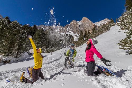 a group of people playing in the snow at Hotel Chalet Sas Morin in Pozza di Fassa