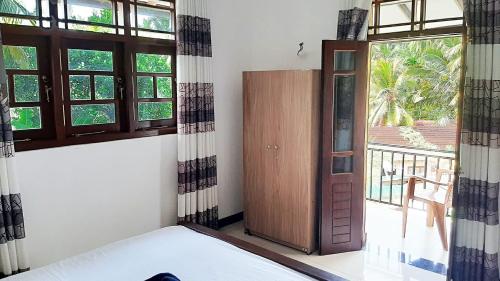 a bedroom with a bed and a door and windows at Sea & Greens Apartments in Unawatuna