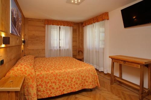 a bedroom with a bed and a table and a television at Hotel Biancaneve in Sauze dʼOulx
