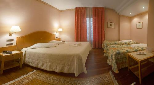 チェラーノにあるHotel Lory & Ristorante Ferraroのベッド2台とテーブル2台が備わるホテルルームです。