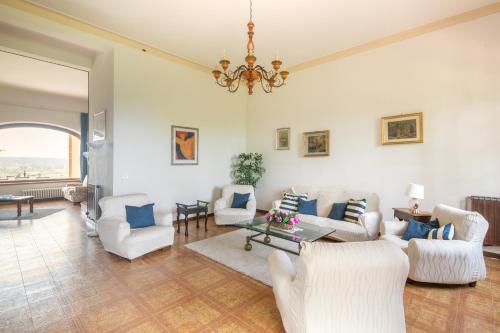 a living room with white furniture and a chandelier at Exclusive 1970s villa with pool and garden by VacaVilla in Montefalcone
