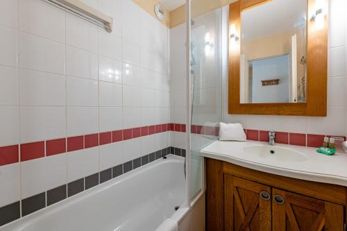 La salle de bains est pourvue d'un lavabo, d'une baignoire et d'un miroir. dans l'établissement Résidence Pierre & Vacances Les Dunes du Médoc, à Soulac-sur-Mer