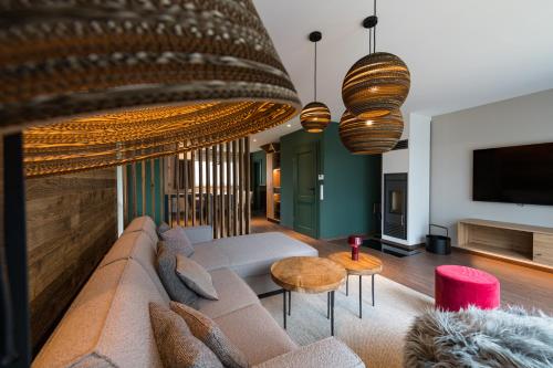 a living room with a couch and a tv at Harz-Urlaubs-Alm Hotel & Ferienhäuser in Clausthal-Zellerfeld