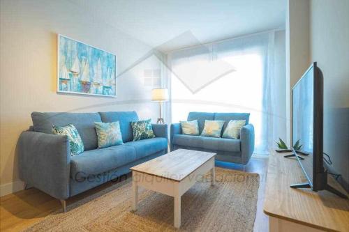 sala de estar con sofá azul y mesa en IyI Apartament, en Ribadesella