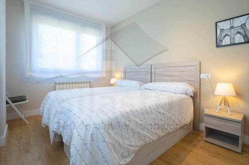 1 dormitorio con cama blanca y ventana en IyI Apartament, en Ribadesella