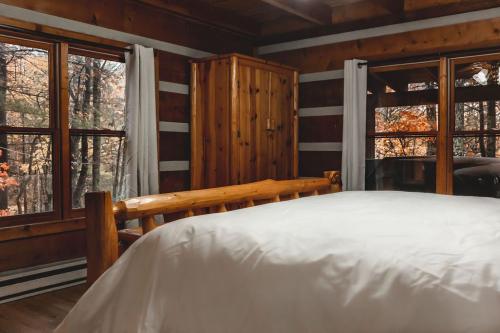 ein Schlafzimmer mit einem Bett und zwei Fenstern in der Unterkunft Pine Crest Cabin at 36 North - Hot Tub in Purlear