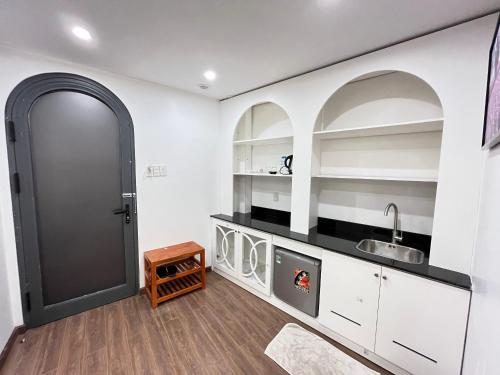 una cocina con armarios blancos y una puerta negra en Tuyet Mai Hotel en Dalat