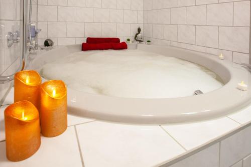 a bathroom with a bath tub with two candles at Relax Hotel & SPA Stuttgart in Stuttgart
