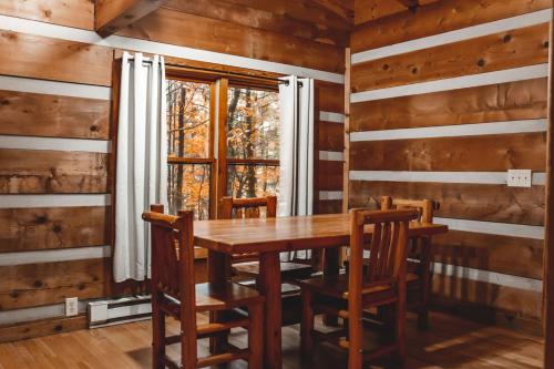 ein Esszimmer mit einem Tisch, Stühlen und einem Fenster in der Unterkunft Pine Crest Cabin at 36 North - Hot Tub in Purlear