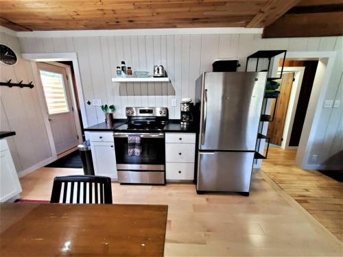 a kitchen with a stainless steel refrigerator and a stove at 3 Cottage Exclusive Retreat-Hot Tubs-Walk to Beach in Traverse City