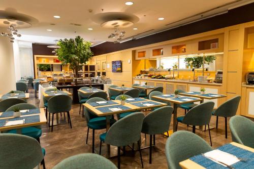 a restaurant with tables and chairs and a kitchen at Ramada Plaza by Wyndham Milano in Milan