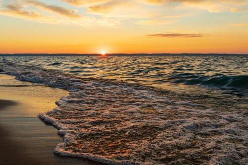 a sunset on the beach with the ocean at 3 Cottage Exclusive Retreat-Hot Tubs-Walk to Beach in Traverse City