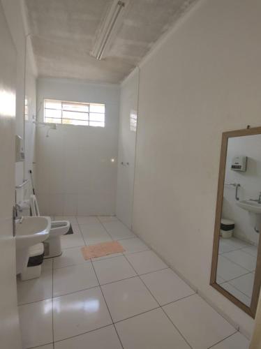 a white bathroom with a mirror and a sink at RUBY HOSPEDAGENS in Indaiatuba