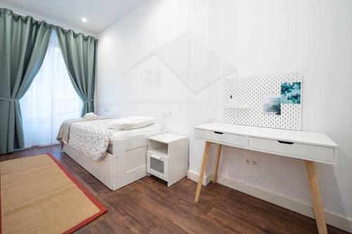 a white bedroom with a bed and a desk at Lavaderu Apartamento in Gijón