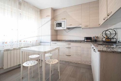 a kitchen with white cabinets and a table and stools at Regalina Vistas a la bahía Lastres in Lastres
