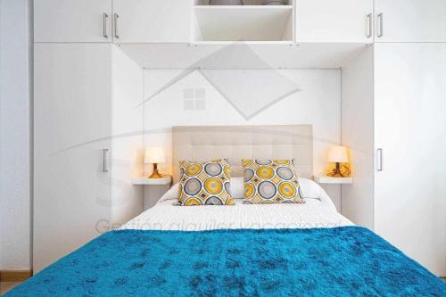 biała sypialnia z niebieskim łóżkiem z 2 lampami w obiekcie Regalina Vistas a la bahía Lastres w mieście Lastres