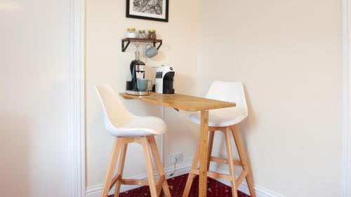 a small table and two white stools in a room at The Ramblers' Rest - Princetown in Princetown