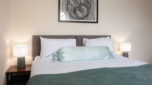 a bedroom with a bed with a blue pillow and two lamps at The Ramblers' Rest - Princetown in Princetown
