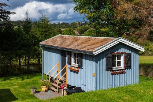 a blue shed with two windows and a staircase at Harz-Urlaubs-Alm Hotel & Ferienhäuser in Clausthal-Zellerfeld